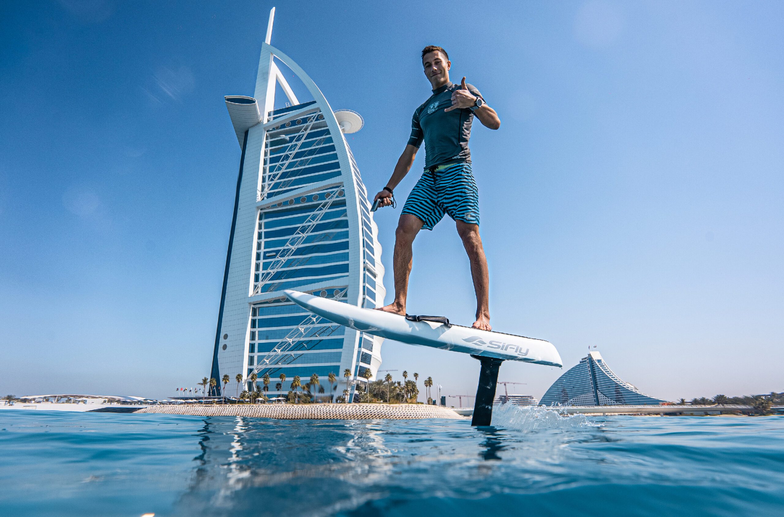 Man posing on E-foil board with a backdrop of Burj Al Arab